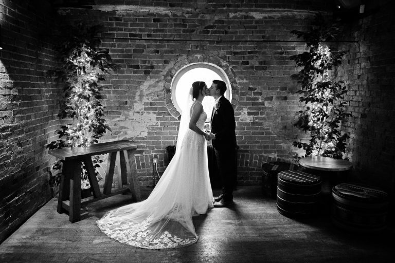 Bride and groom kiss in the moon window at at Shustoke Barn