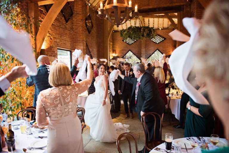 Candid photo of wedding guests celebrating the entrance of the bride and groom with spinning their napkins in the air.