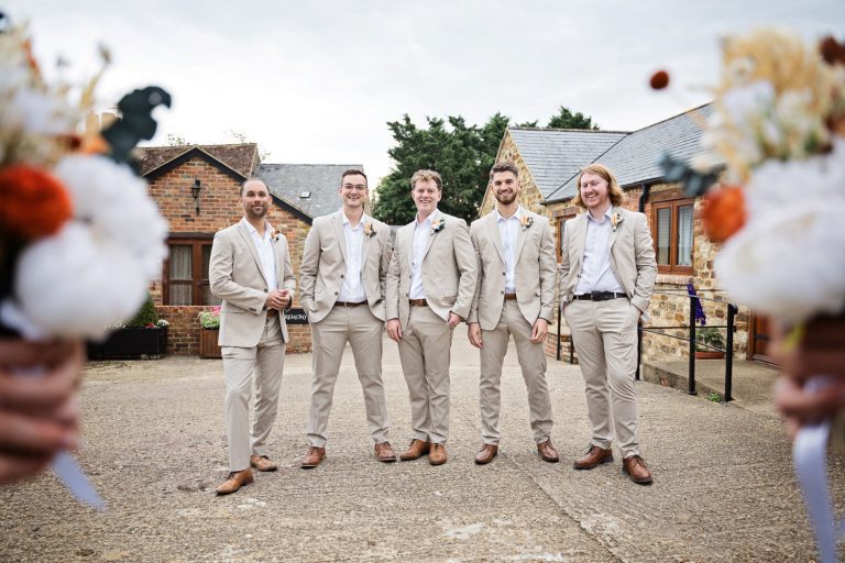 Groomsmen standing. Flower bouquets either side the picture to add a bit of jazz.