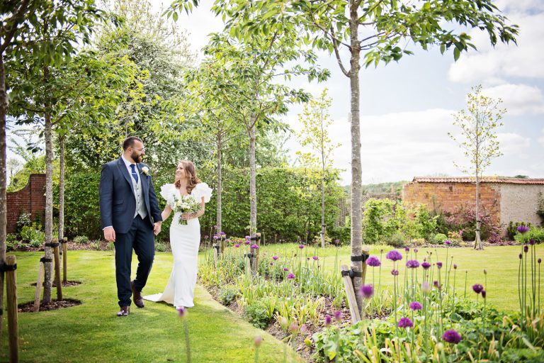 Bride and groom walking in the summer gardens.