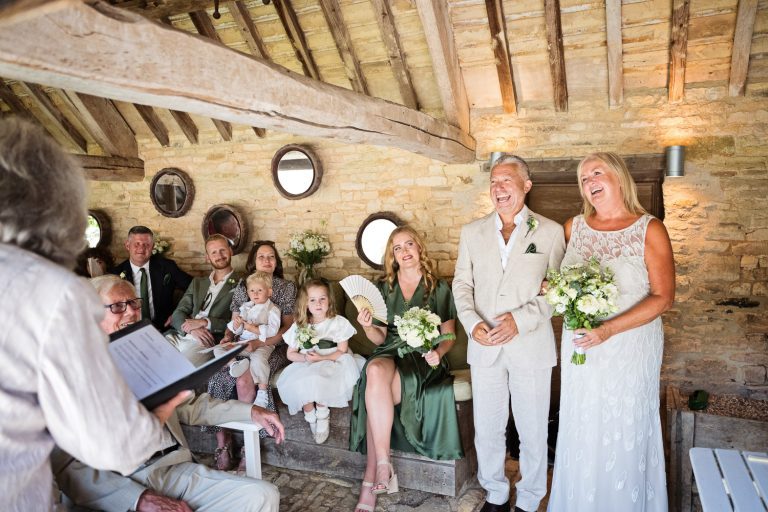 Relaxed photo of bride and groom laughing out loud during their wedding ceremony.