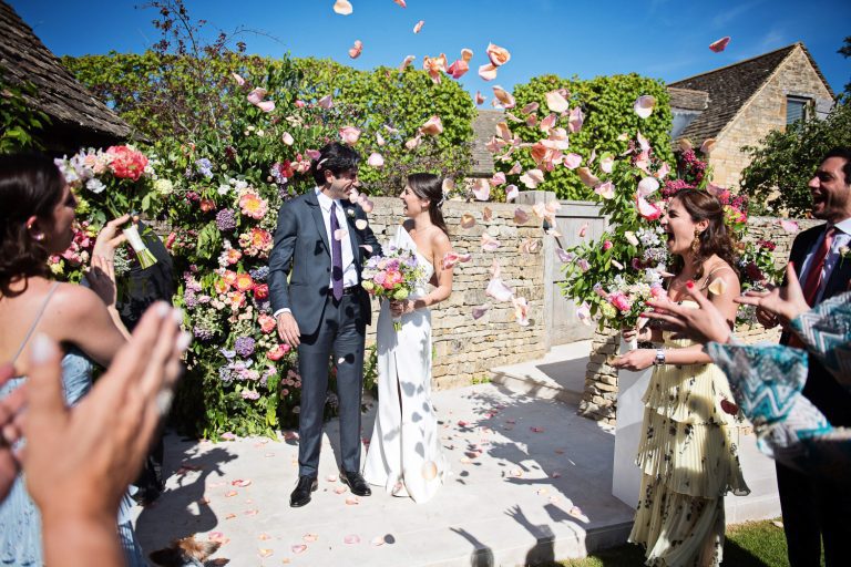 Candid storytelling photograph of wedding guests throwing flower petals at the bride and groom in celebration of them getting married at Temple Guiting Manor.