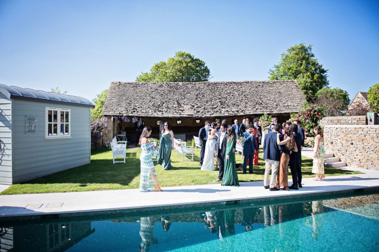 Wedding guests congregate by the swimming pool at Temple Guiting Manor.