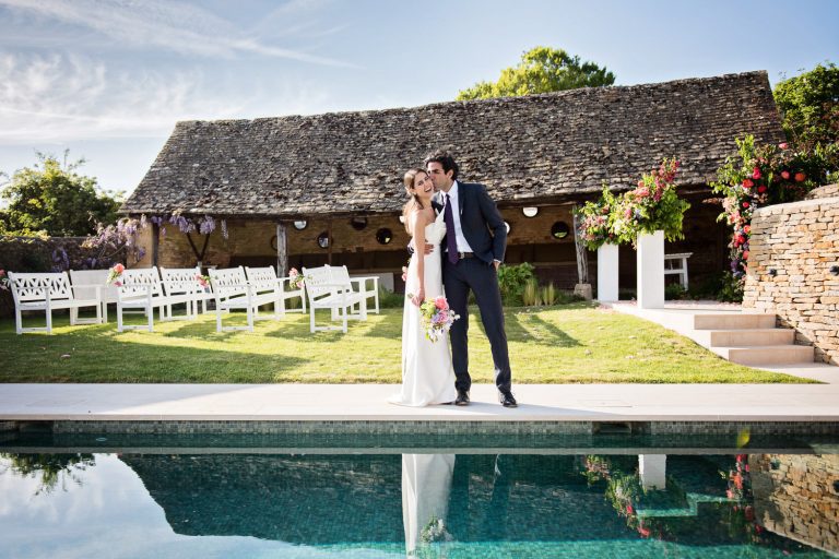 Bride and groom share a moment together by a Cotswold swimming pool.
