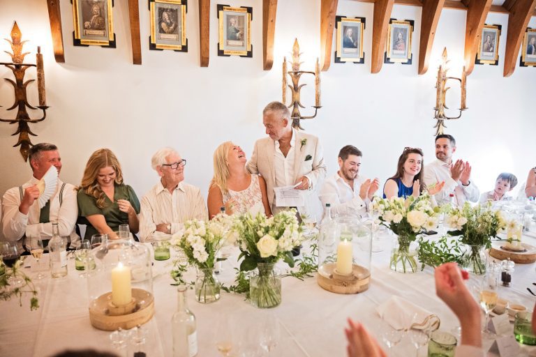 Groom delivers his wedding speech to guests who are smiling and clapping.