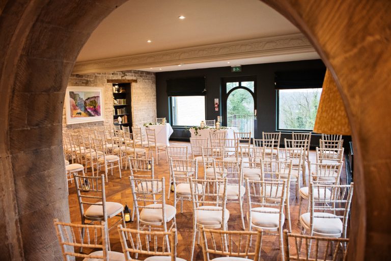 Wedding ceremony set up at The Bear at Rodborough look through an arch.
