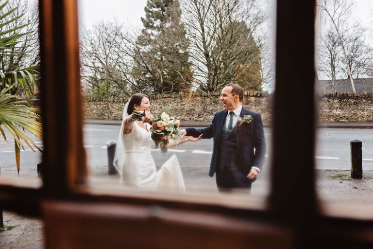 Looking through a door window spotting the bride and groom having a fun moment together.
