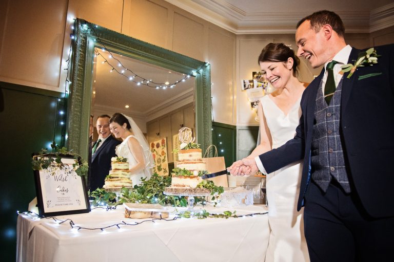 Relaxed photo of the bride and groom cutting the wedding cake.