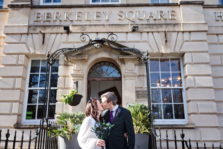 Candid photo of Bride and groom kissing outside The Berkeley Square Hotel