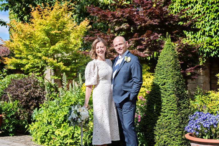 Bride and groom smiling in the garden courtyard.