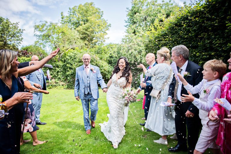 Bride and groom get showered with confetti by their wedding guests.