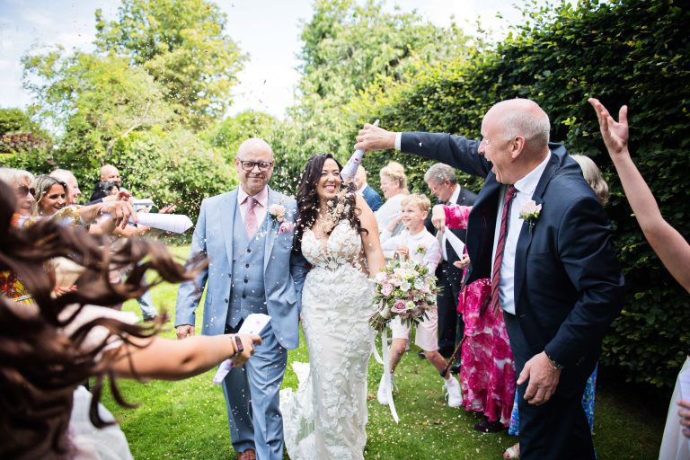 Bride and groom get showered with confetti by their wedding guests.