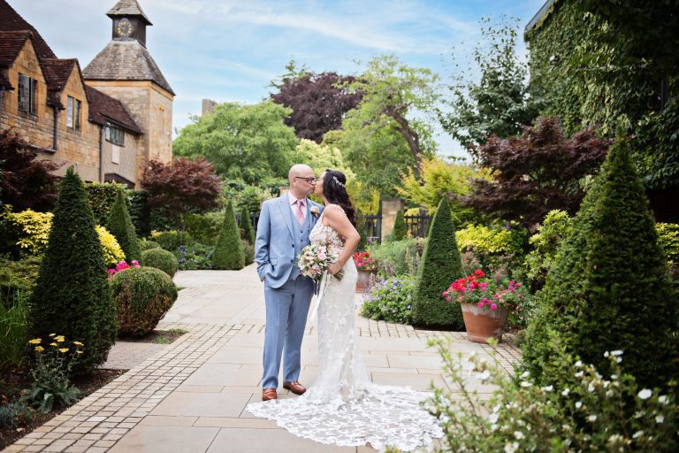 Bride and groom kiss in the courtyard at Lygon Arms, Broadway.