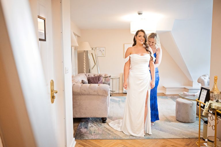 Samantha J Alterations helping the bride get into her wedding dress.