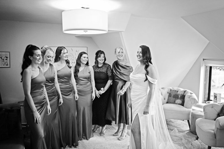 B&W photo of the bride in front of the bridesmaids as they are getting ready.