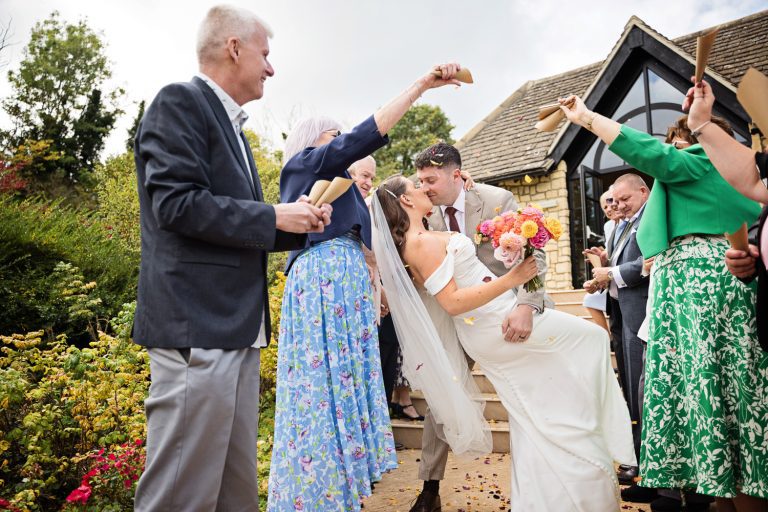 Bride and groom trying the dip as they walk down the steps whilst wedding guests are showering them with confetti.