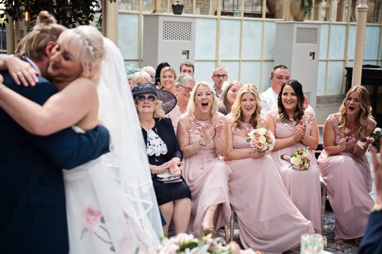 Bridesmaids whooping and clapping the bride and groom at their announcement of being husband and wife.