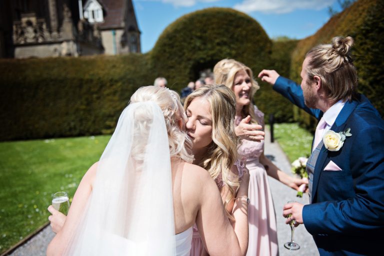 Candid photo of bride and groom getting hugged by the bridesmaids.