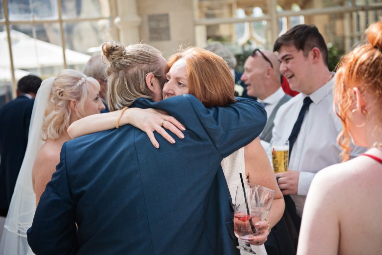 Candid photo of the groom being hugged by another wedding guest.