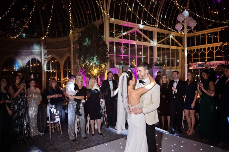 Bride and groom do their first dance in The Orangery at Tortworth Court. Candid photo with friends and family watching the bride and groom.