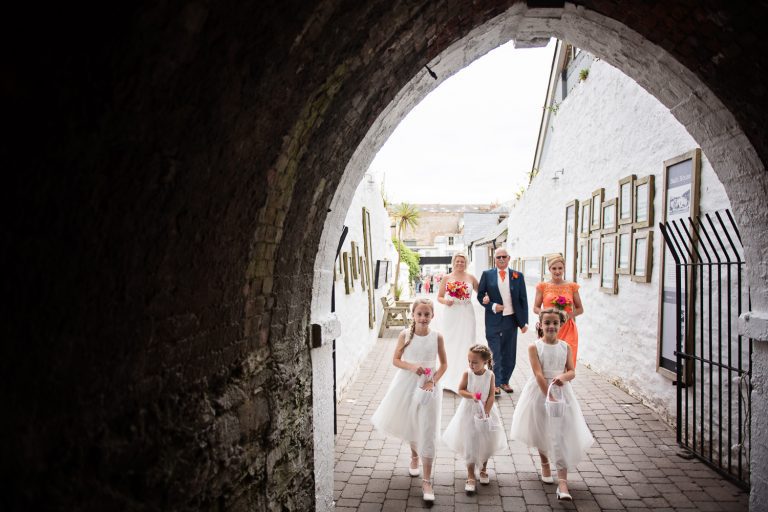 Cute photo of the flower girls entering the Tunnels at Tunnel Beach. Bride and her father walking behind.