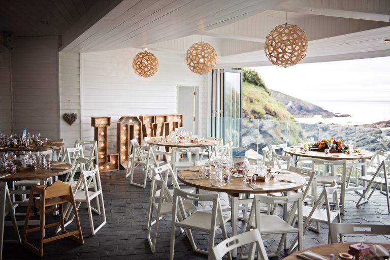 Wedding breakfast laid out at Tunnel Beach. The doors are also open, and lead you out to a impressive view of the Devon coastline.