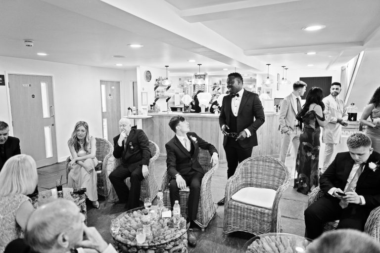 Storytelling candid photograph of wedding guests chatting and mingling. B&W.
