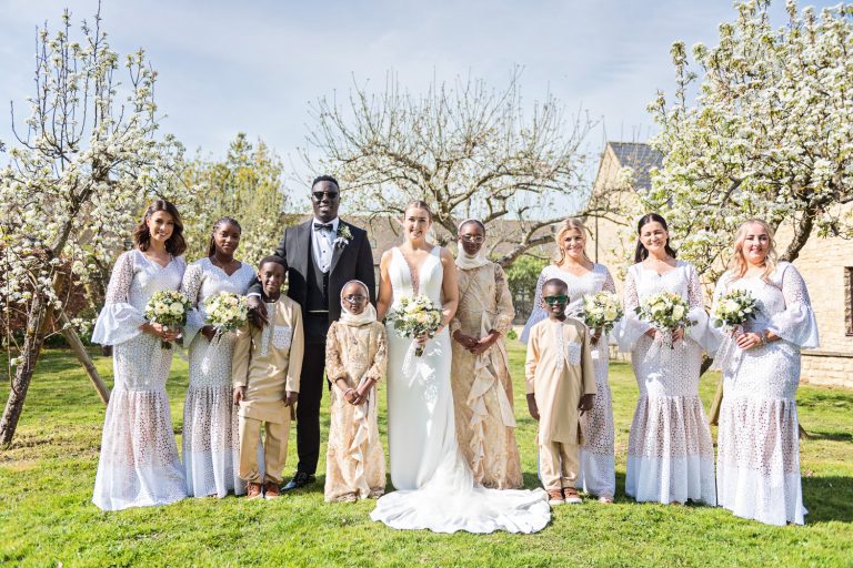 Bridal party standing on the lawn in front of flowering trees.