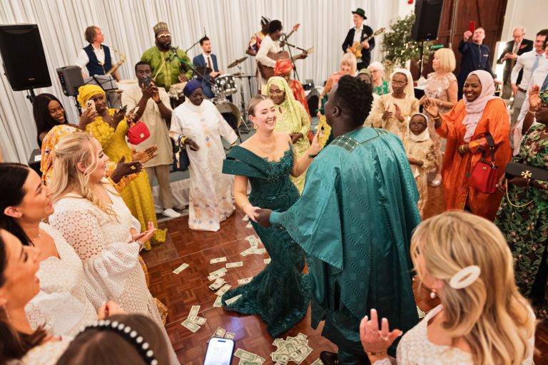 Bride and groom dance with their friends and family surrounding them.