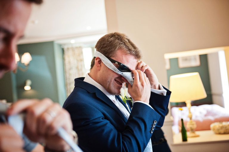 Groomsman putting his tie on.