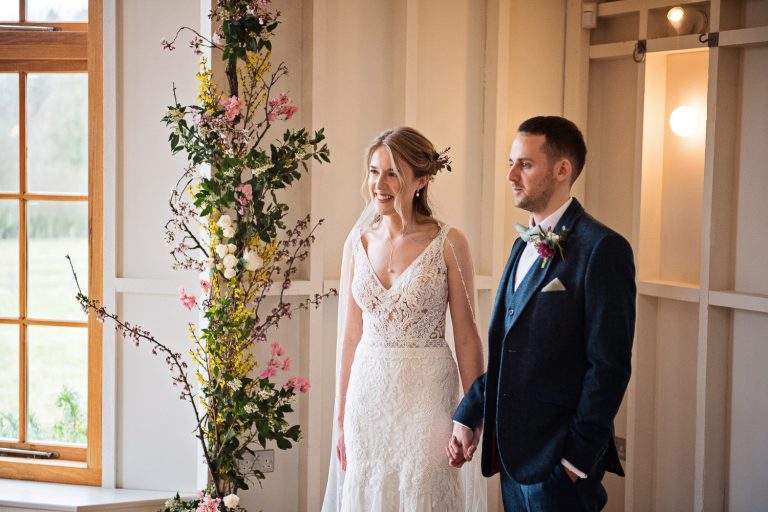 Candid pic of bride and groom holding hands during the wedding ceremony.