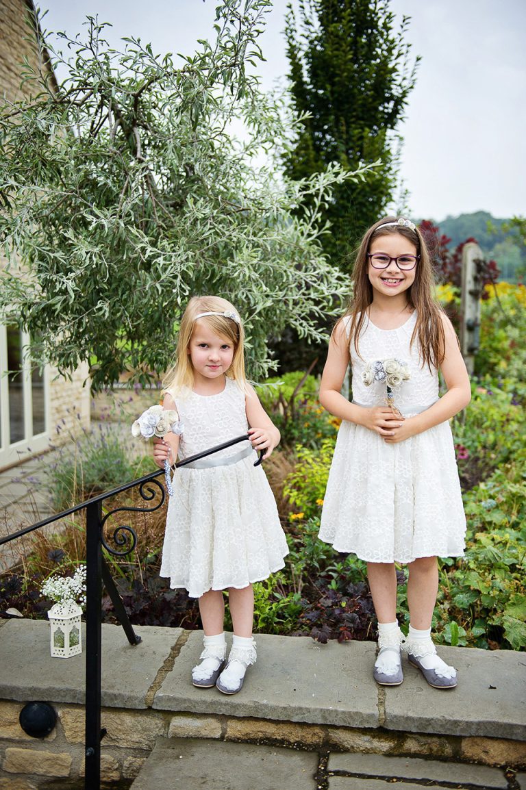 Portrait pic of two flower girls standing on a wall.