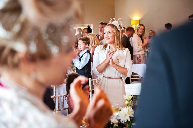 Candid, storytelling image of wedding guests clapping the bride and groom at Hyde House.