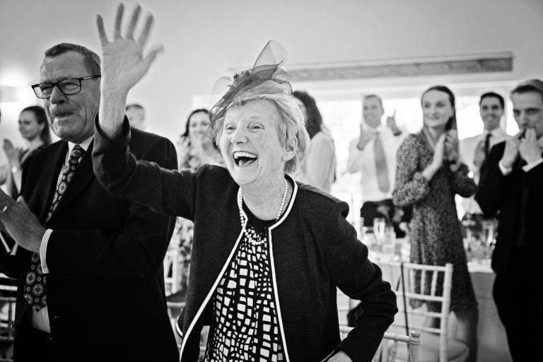 B&W storytelling photo of grandma and guests cheering the bride and groom.