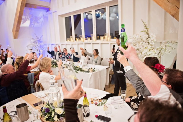Wedding guests raise a glass at the end of wedding speeches.