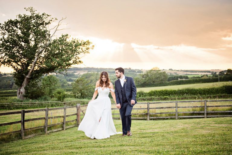 Bride and groom stand looking at the magnificent sunset at Stow On The Wold