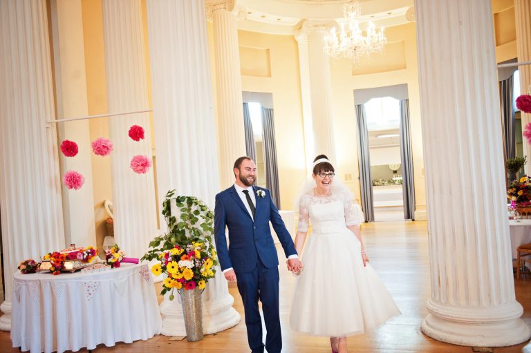 Bride and groom get announced for their wedding breakfast - both are smiling.