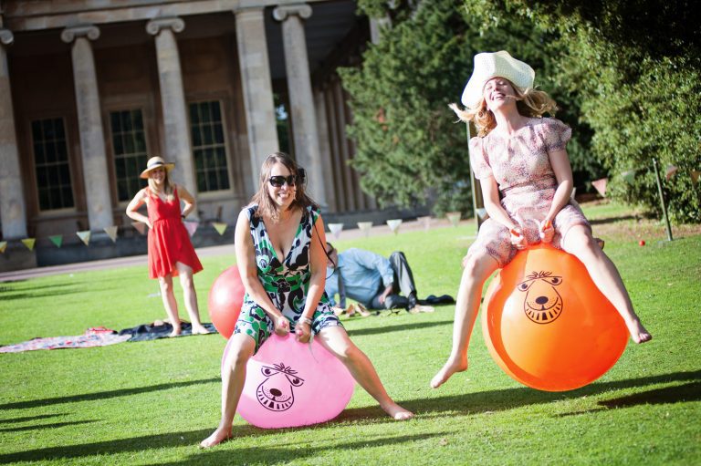Wedding guests race on Space Hoppers. With the Pittville Pump Rooms behind.