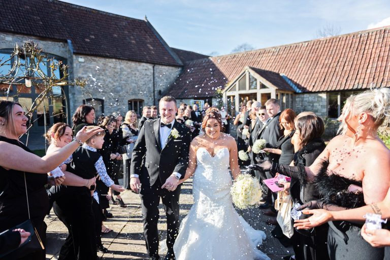 Bride and groom getting showered by confetti at Priston Mill.