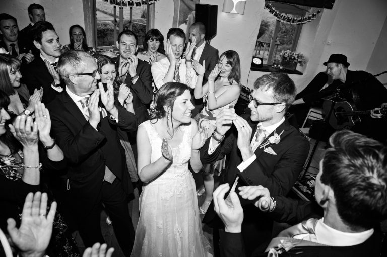 Bride and groom cheer with their wedding guests at Priston Mill.