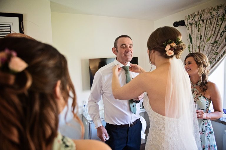 Candid photo of the bride sorting her dads collar and tie out at The Slaughters Country Inn