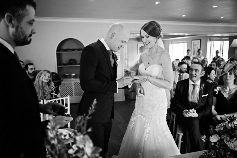 Groom puts on a wedding ring on his brides finger at The Slaughters Country Inn