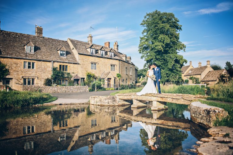 Bride and groom at their wedding at The Slaughters Country Inn standing on the famous bridge in Lower Slaughter.