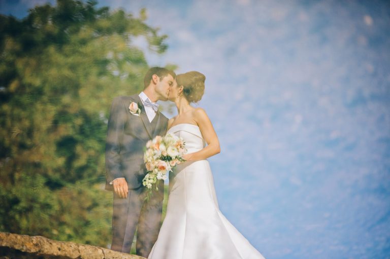 Reflection of the bride and groom in the water at the Cotswold village Lower Slaughter