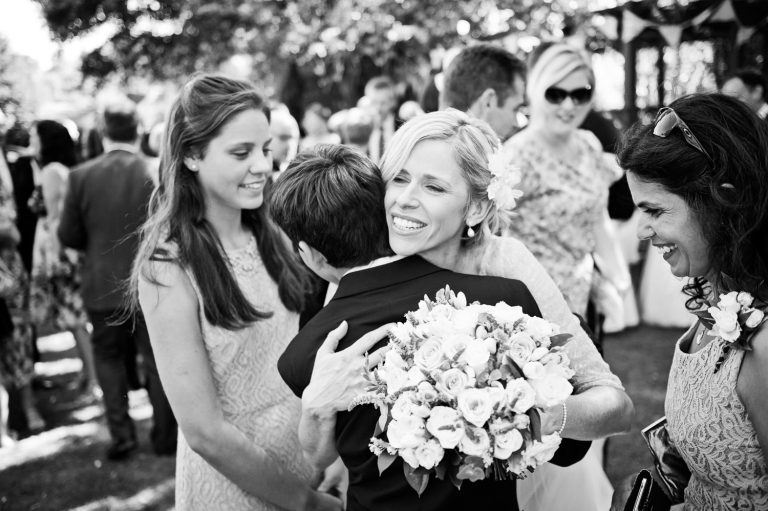 B&W candid photo of the bride hugging a guest.