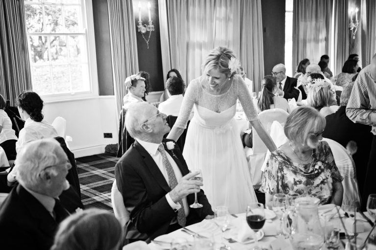 Candid photo of bride chatting to her wedding guests. B&W image.