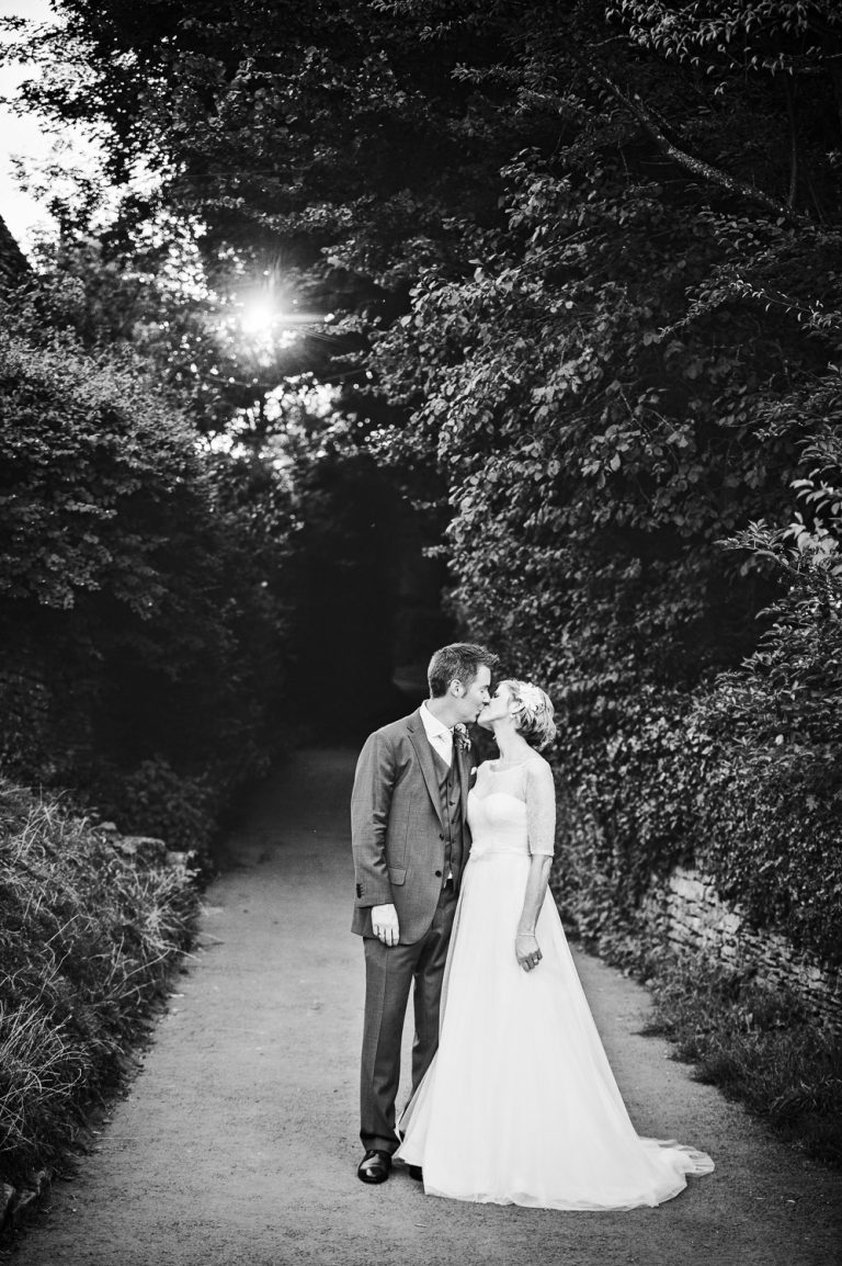 B&W portrait photo of bride and groom kissing.