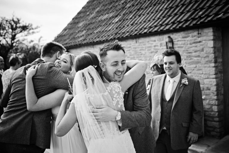 Documentary photo of wedding guests congratulating the bride and groom at Kingscote Barn.