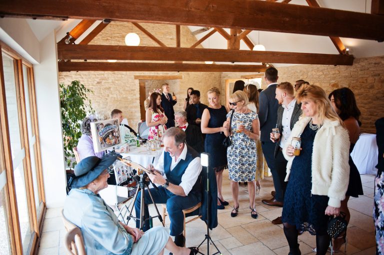 Tony Toons aka Anthony Marriot drawing a caricature of a guest at a wedding at Kingscote Barn.