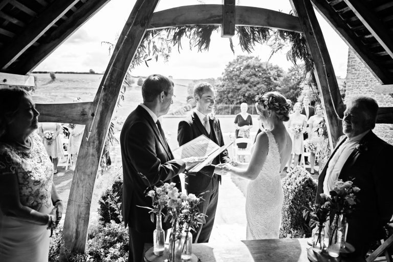 Story telling image of an outdoor ceremony taking place at Kingscote Barn. B&W image.